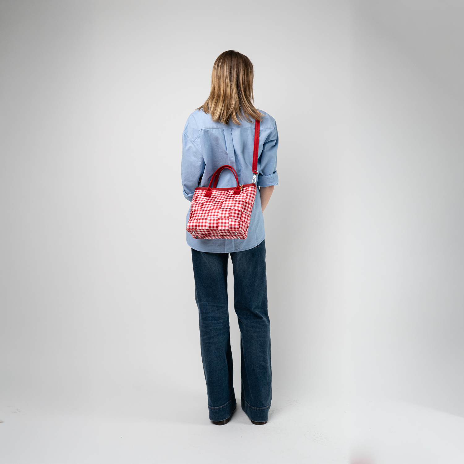 A Red Gingham Crossbody Tote being used by a model