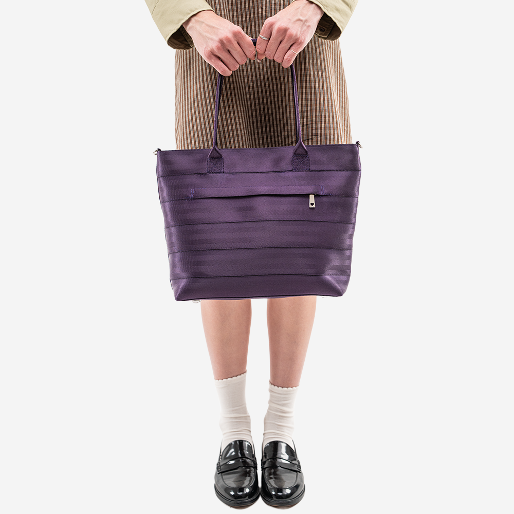 The Medium Streamline Tote in Blackberry being held by a model