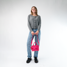 A Woven Petite Tote in Melon being held in a Model's hands
